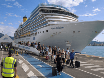 Tornare a casa dopo una crociera: Costa Deliziosa ferma al porto con passeggeri che scendono dalla passerella