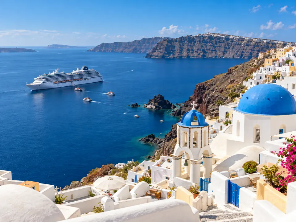 Santorini con cupole blu e nave da crociera nella caldera